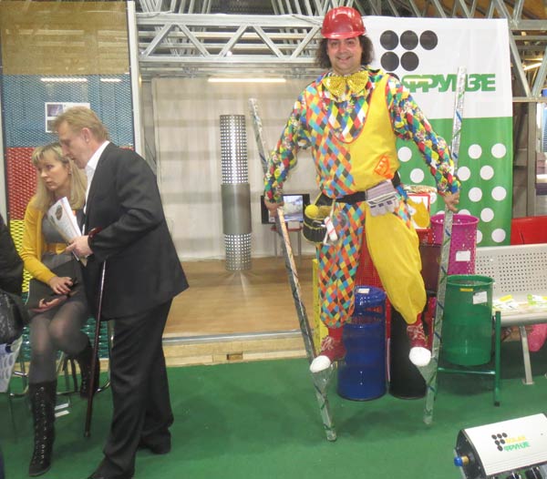 клоун на ходулях ходит по выставке