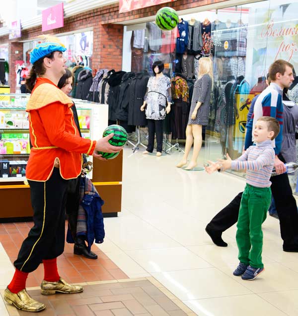 клоун играет в мячик с ребенком