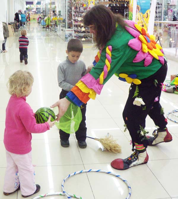 клоун ловит у детей мяч в сачок